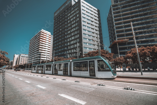 Wide-angle view of the modern streetcar in urban settings  contemporary five-car tram on the city street with a road in the foreground and huge residential houses behind © skyNext