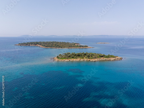 Two small islands surrounded with blue sea water with mountains in background. Drone aerial view © Zoran