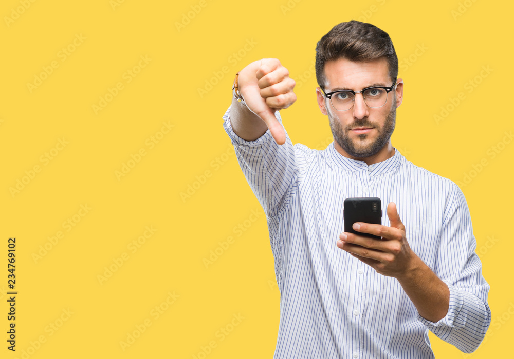 Young handsome man texting using smartphone over isolated background with angry face, negative sign showing dislike with thumbs down, rejection concept Young handsome man texting using smartphone over isolated background with angry face, negative sign showing dislike with thumbs down, rejection concept