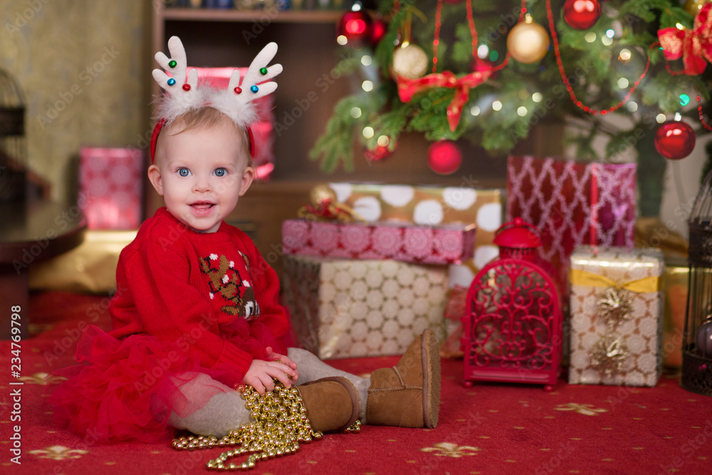 Christmas scene of baby girl posing with presents in studio shoot. Happy smile child celebrating new year holiday.