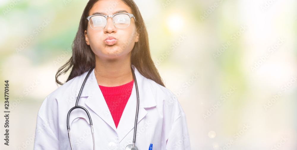 Young arab doctor woman over isolated background puffing cheeks with funny face. Mouth inflated with air, crazy expression. Young arab doctor woman over isolated background puffing cheeks with funny face. Mouth inflated with air, crazy expression.