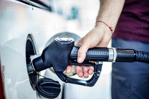 Man fulling tank with fuel at bokeh background