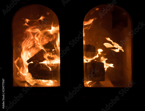 Raging forks of flame in fireplace behind the protective glass screen
