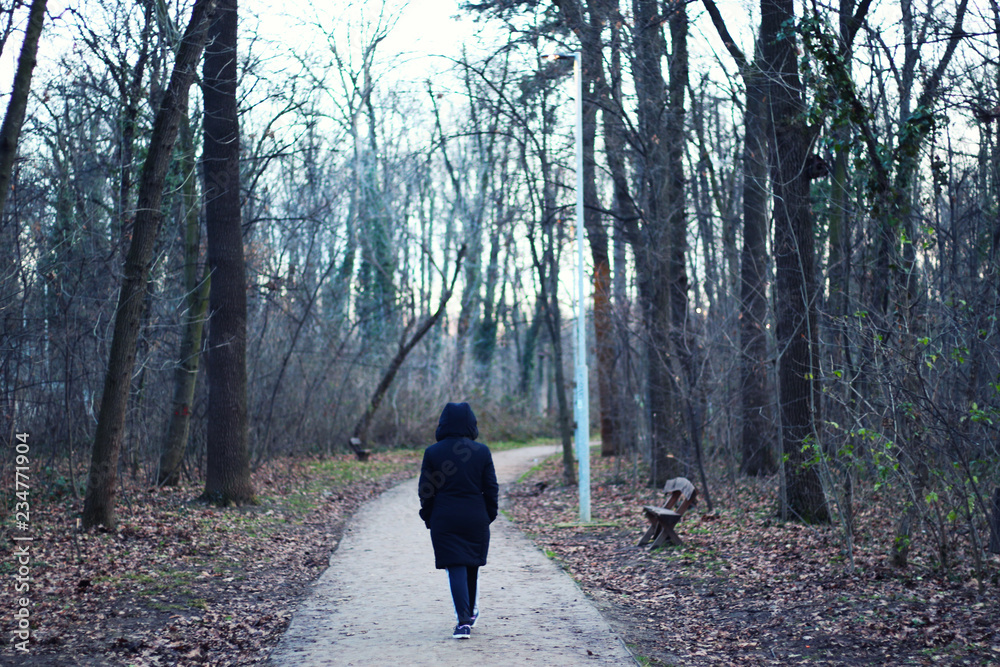 Woman is walking through forest in wintertime. Alone woman is going in cold day
