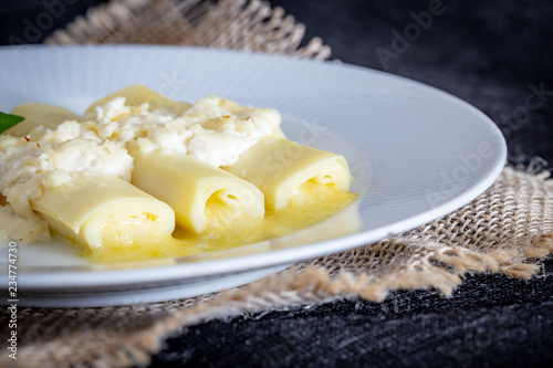 Italian caneloni with bechamel sauce and cheese on rustic background. photo