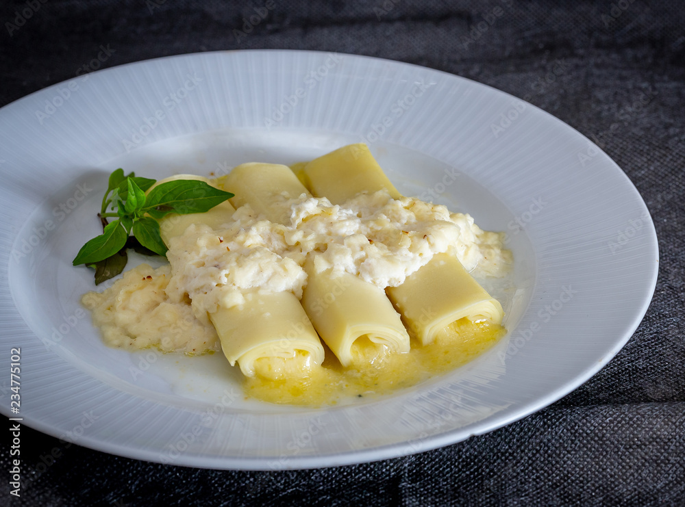 Italian caneloni with bechamel sauce and cheese on rustic background. Italian caneloni with bechamel sauce and cheese on rustic background.
