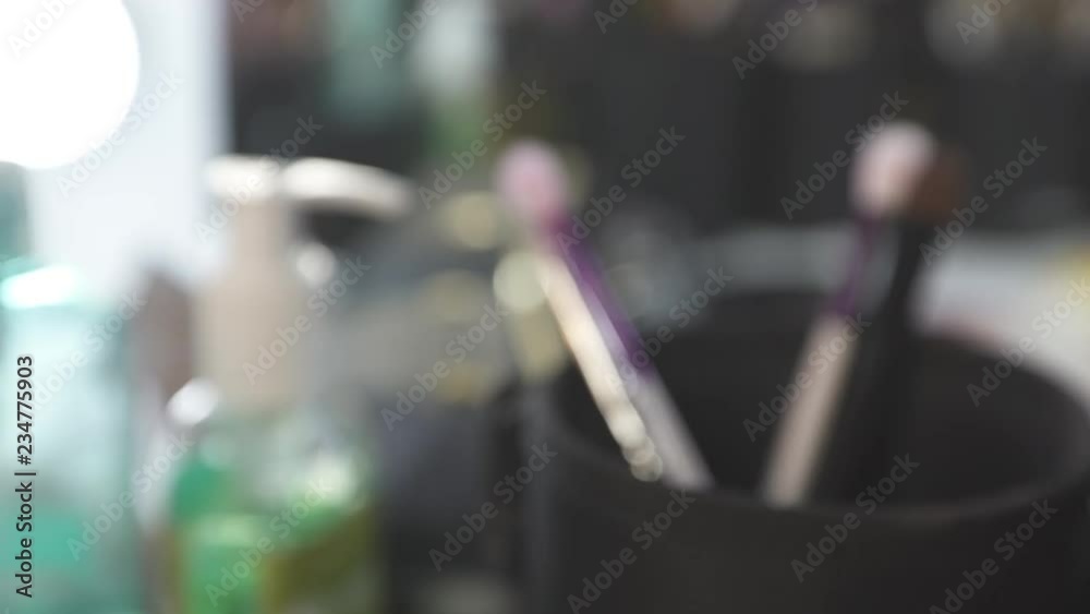 Various sets of cosmetic brushes in black cups on the table against blurred background. Various sets of cosmetic brushes in black cups on the table against blurred background.
