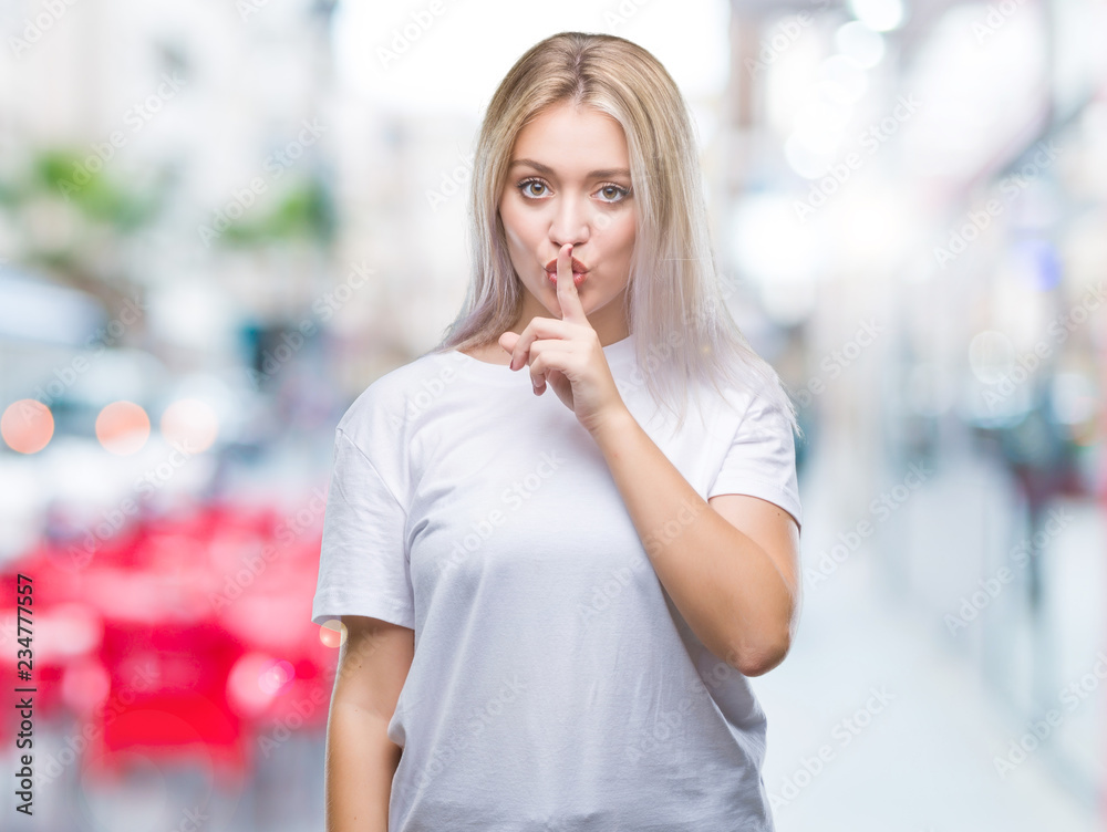 Young blonde woman over isolated background asking to be quiet with finger on lips. Silence and secret concept.