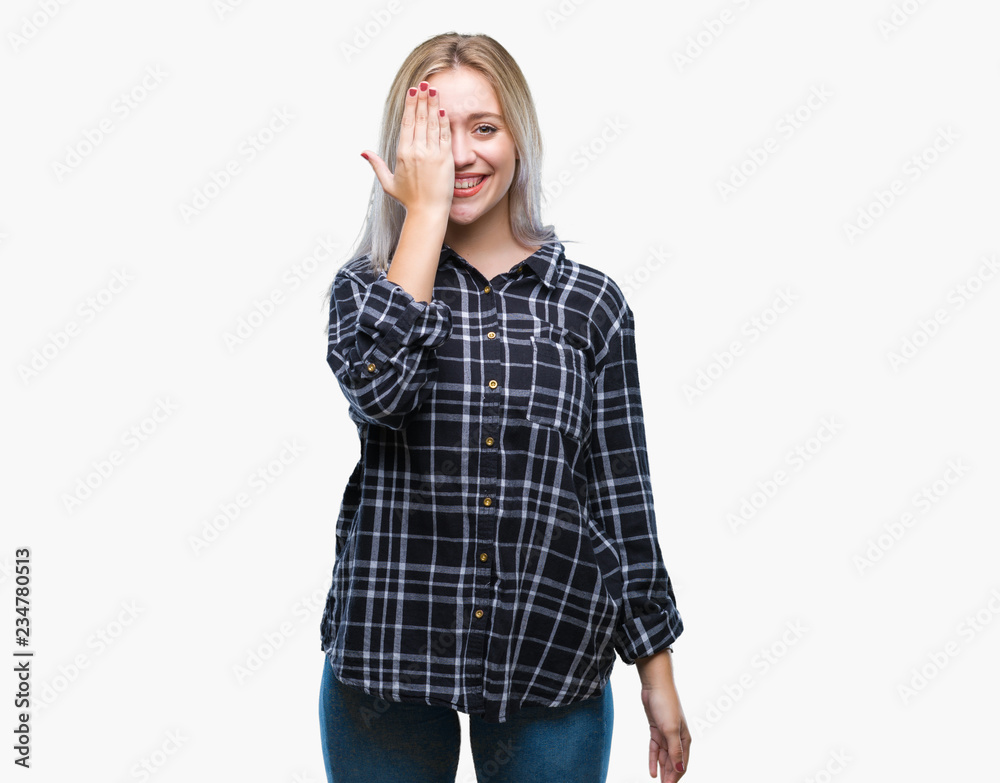 Young blonde woman over isolated background covering one eye with hand with confident smile on face and surprise emotion. Young blonde woman over isolated background covering one eye with hand with confident smile on face and surprise emotion.