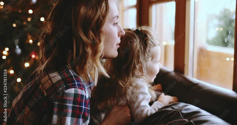 Mother and Daughter Having Fun on Christmas Morning. SLOW MOTION. Precious family moment, young mom playing with her toddler daughter by the window, winter landscape. 