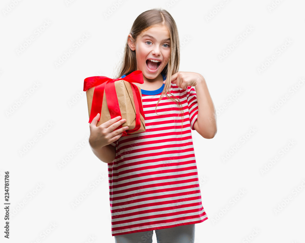 Young beautiful girl giving christmas or valentine gift over isolated background with surprise face pointing finger to himself Young beautiful girl giving christmas or valentine gift over isolated background with surprise face pointing finger to himself