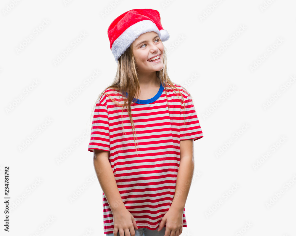 Young beautiful girl wearing christmas hat over isolated background looking away to side with smile on face, natural expression. Laughing confident. Young beautiful girl wearing christmas hat over isolated background looking away to side with smile on face, natural expression. Laughing confident.