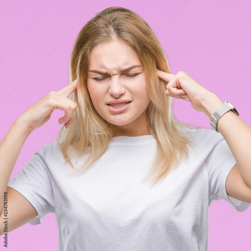Young caucasian woman over isolated background covering ears with fingers with annoyed expression for the noise of loud music. Deaf concept.