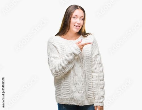 Young beautiful caucasian woman wearing winter sweater over isolated background cheerful with a smile of face pointing with hand and finger up to the side with happy and natural expression on face
