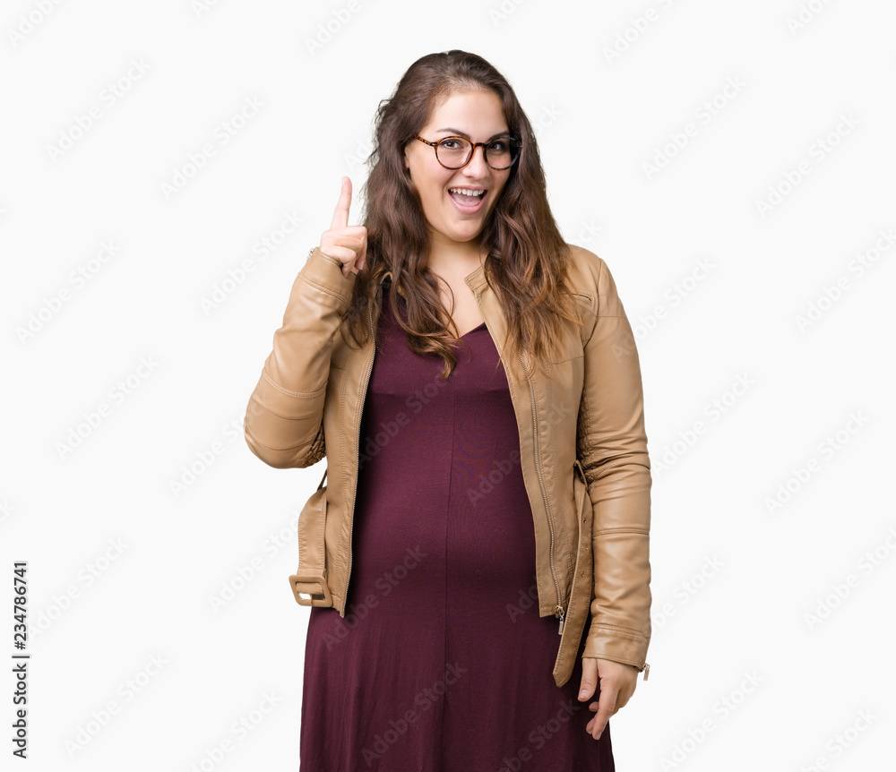 Beautiful plus size young woman wearing a dress and leather jacket over isolated background pointing finger up with successful idea. Exited and happy. Number one. Beautiful plus size young woman wearing a dress and leather jacket over isolated background pointing finger up with successful idea. Exited and happy. Number one.
