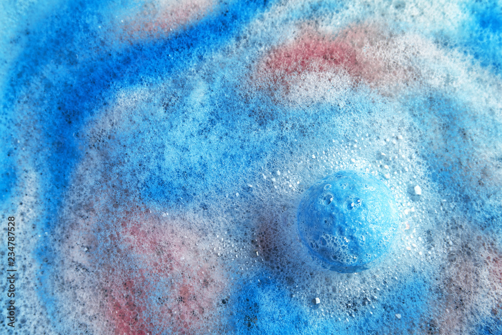 Dissolving color bath bomb in water, top view. Space for text