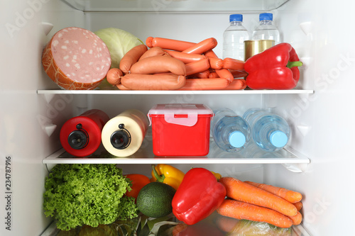 Open refrigerator with many different products, closeup