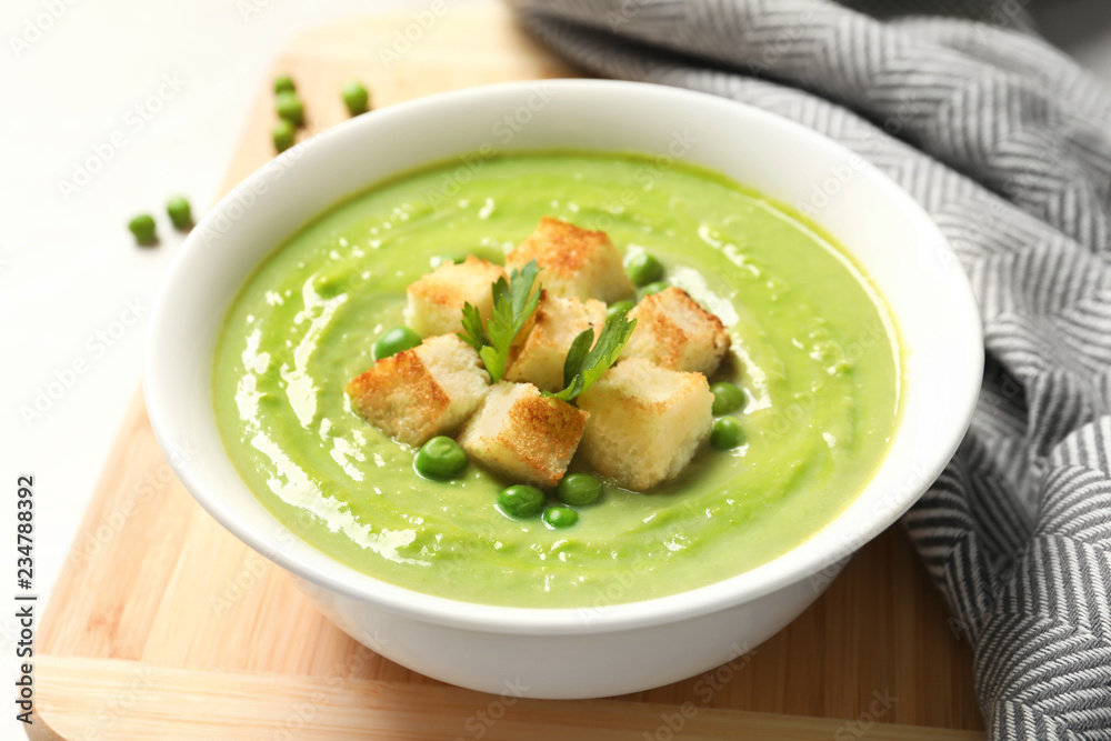 Fresh vegetable detox soup made of green peas with croutons in dish served on table Fresh vegetable detox soup made of green peas with croutons in dish served on table