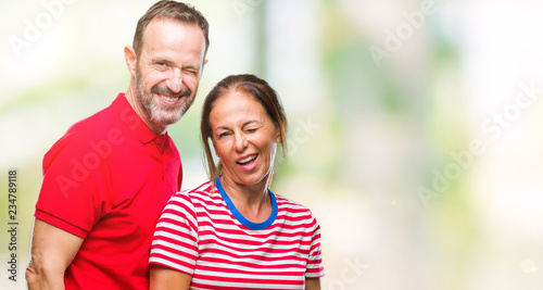 Middle age hispanic couple in love over isolated background winking looking at the camera with sexy expression, cheerful and happy face.