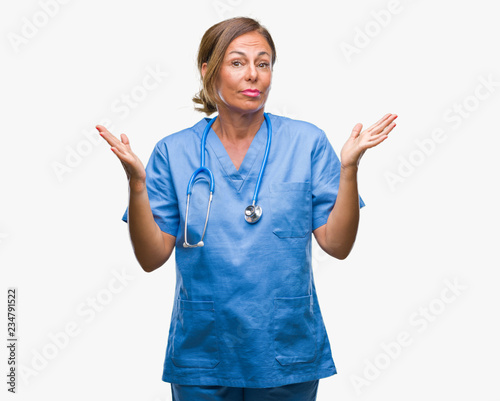 Middle age senior nurse doctor woman over isolated background clueless and confused expression with arms and hands raised. Doubt concept.