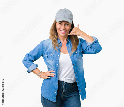 Beautiful middle age woman wearing sport cap over isolated background smiling doing phone gesture with hand and fingers like talking on the telephone. Communicating concepts.