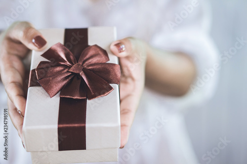 closeup woman hand giving gift box on new year day 