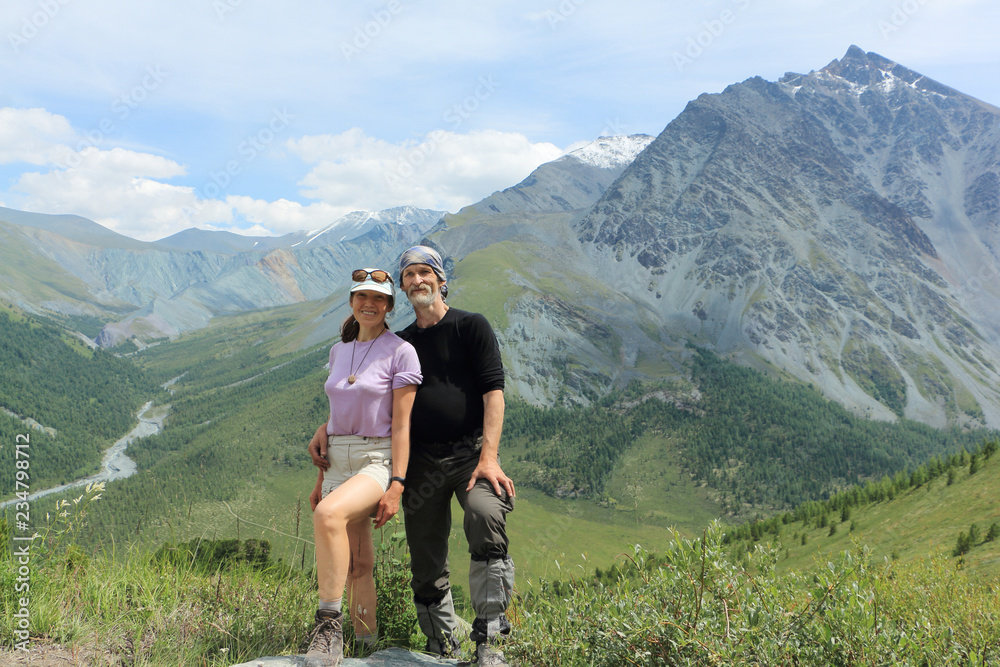 Happy man and woman standing on the Kara-Turek pass on the background of mountains, Altai Mountains, Russia