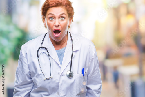 Senior caucasian doctor woman wearing medical uniform over isolated background afraid and shocked with surprise expression, fear and excited face.