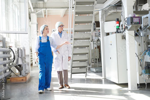Full length portrait of young female worker giving tour of factory to senior woman  copy space