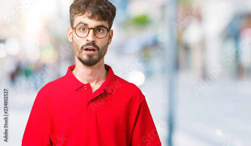 Young handsome man wearing glasses over isolated background afraid and shocked with surprise expression, fear and excited face.