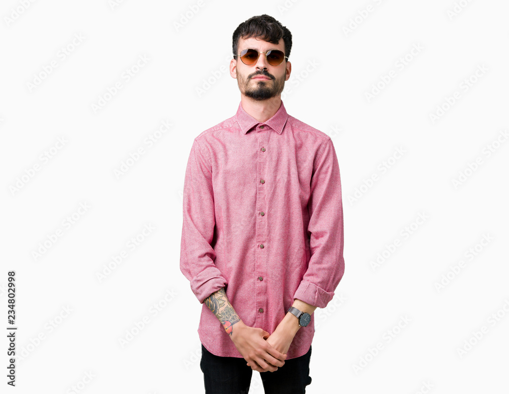Young handsome man wearing sunglasses over isolated background with serious expression on face. Simple and natural looking at the camera. Young handsome man wearing sunglasses over isolated background with serious expression on face. Simple and natural looking at the camera.