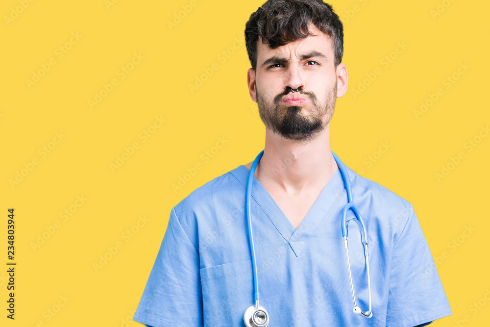 Young handsome nurse man wearing surgeon uniform over isolated background puffing cheeks with funny face. Mouth inflated with air, crazy expression. Young handsome nurse man wearing surgeon uniform over isolated background puffing cheeks with funny face. Mouth inflated with air, crazy expression.