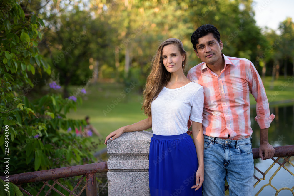 Multi ethnic couple standing together on the bridge of peaceful 