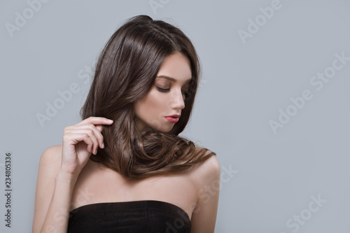 Fashion woman with curly shiny long hair. Gray background