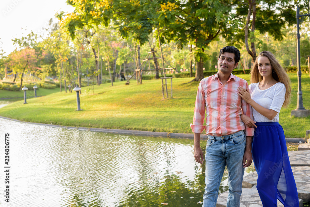 Multi ethnic couple thinking while standing on stone path in the Multi ethnic couple thinking while standing on stone path in the