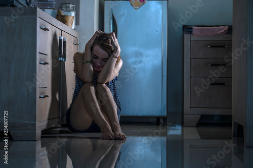 young depressed and overwhelmed woman desperate at home kitchen floor feeling sad and scared suffering depression and anxiety problem domestic violence concept photo