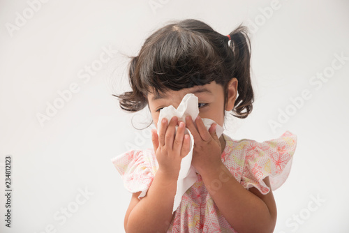 Asian little girl with handkerchief. Sick child has runny nose isolated on white background