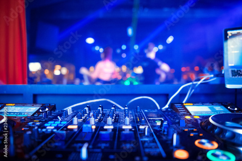 DJ mixer on the table background the night club and dancing people