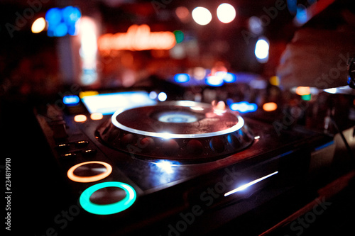 DJ mixer on the table background the night club and dancing people