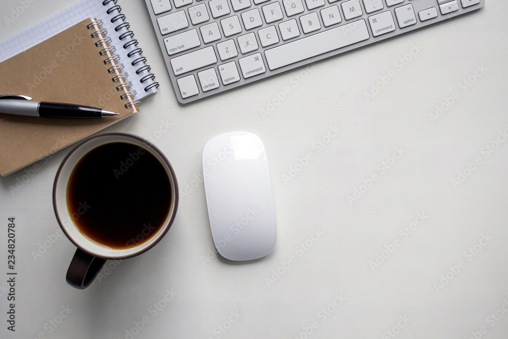 White wooden table with keyboard, pen, craft notebook, mouse and a cup of coffee. Workspace top view with copy space. White wooden table with keyboard, pen, craft notebook, mouse and a cup of coffee. Workspace top view with copy space.