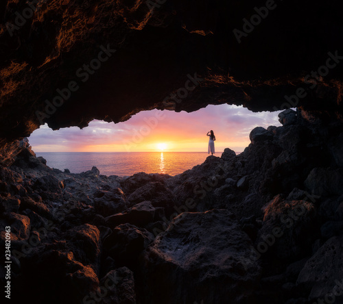 Girl watching a sunset through a cave at Le Souffleur in Saint-Leu, Reunion Island