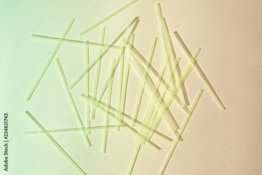 Green plastic straws on light background. Event and party supplies. Earth pollution concept Green plastic straws on light background. Event and party supplies. Earth pollution concept