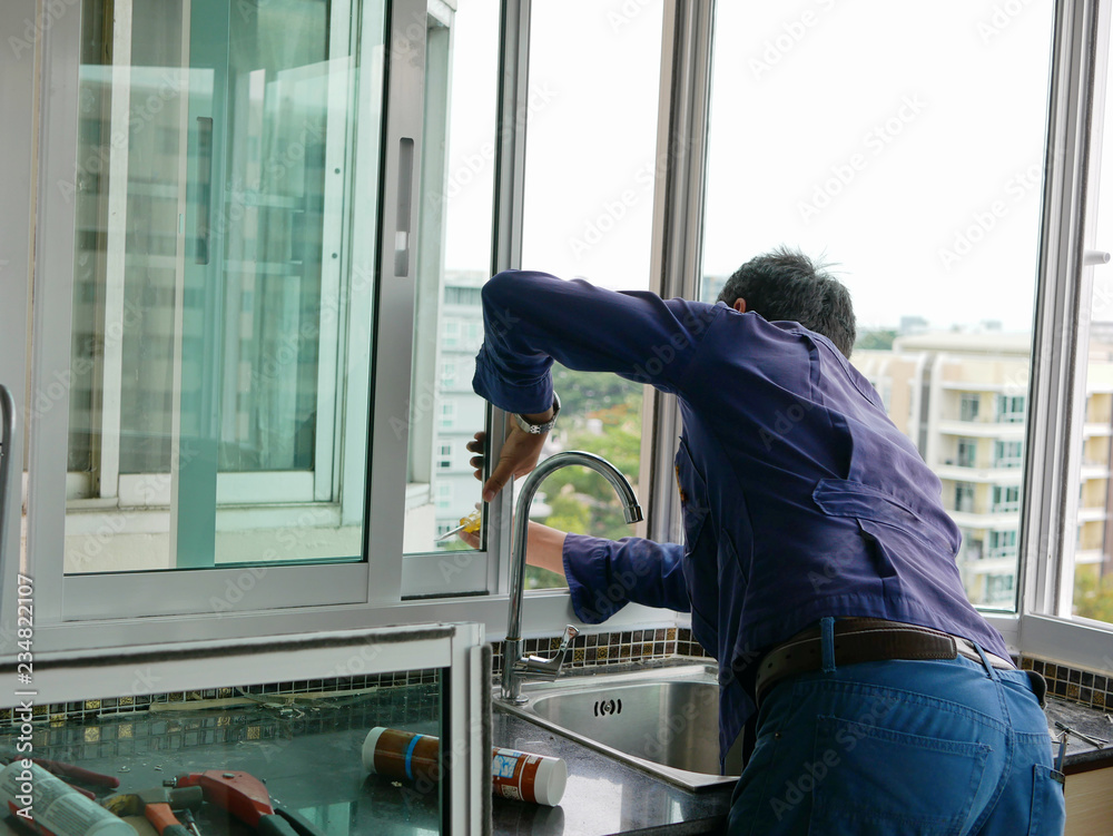 Asian technician installing a sliding window for high rise apartment building Asian technician installing a sliding window for high rise apartment building