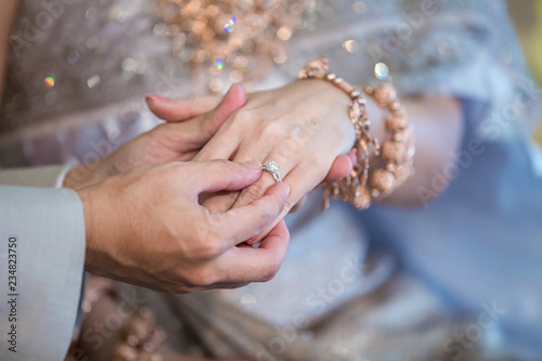 Wedding rings. He Put the Wedding Ring on Her. Close up Groom Put the Ring on bride. thai wedding ceremony and thai wedding decoration.