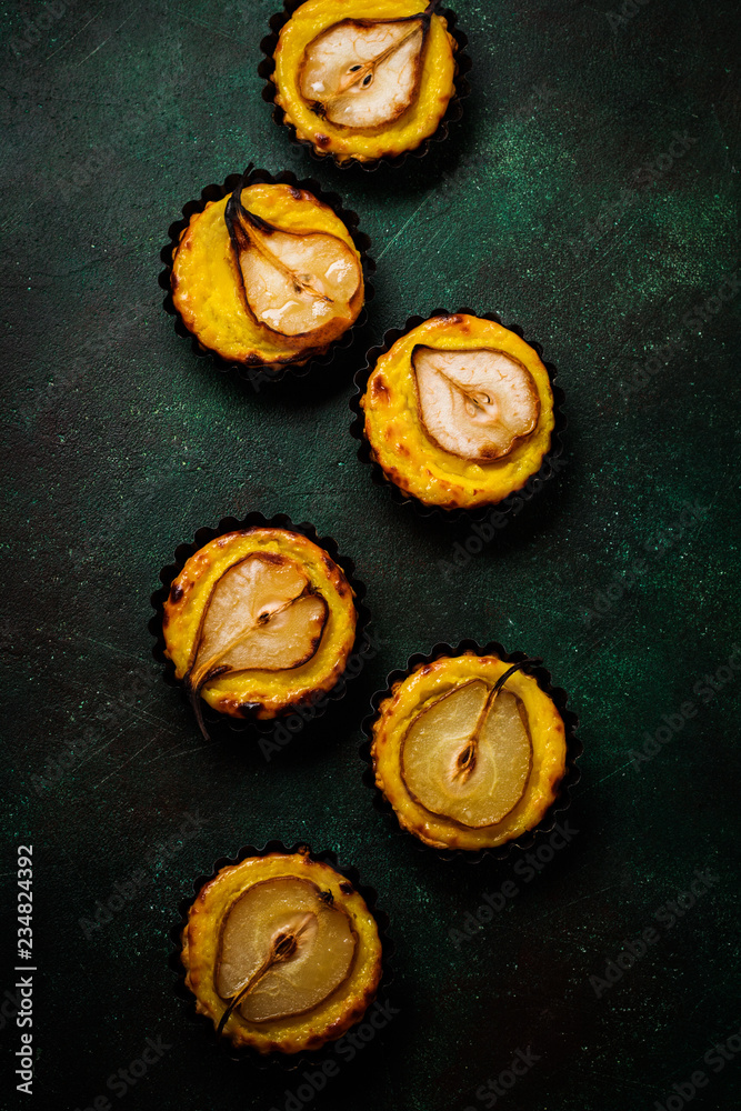 Pears and custard mini tarts on a dark green concrete old table background. Top view. Pears and custard mini tarts on a dark green concrete old table background. Top view.