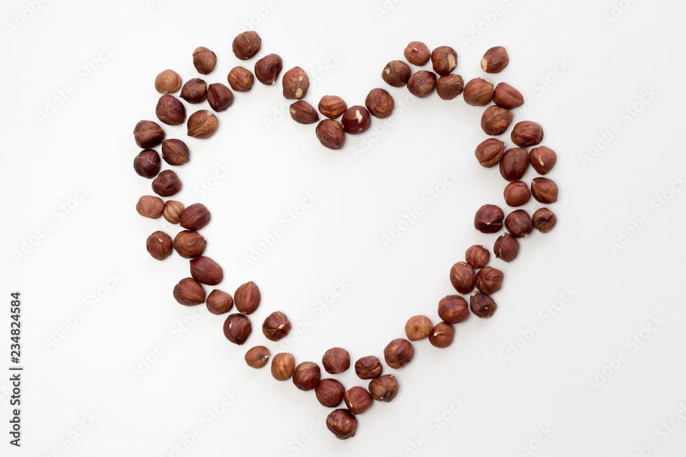 Heart shape from hazelnut on white background. Flat lay, top view, copy space Heart shape from hazelnut on white background. Flat lay, top view, copy space