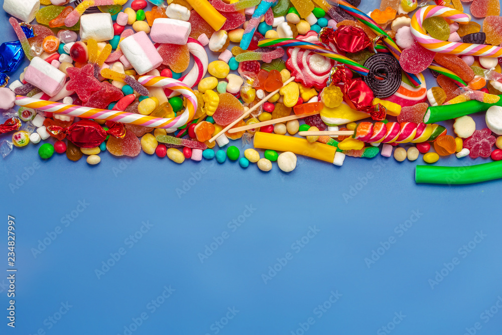 Fototapeta premium Colorful candies on table on blue background