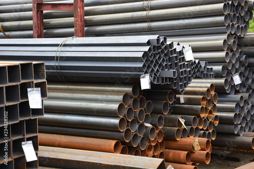 Metal rolling. A round and square tube with labels for text are stacked in storage for sale and loading in stock in the open air. Close-up.