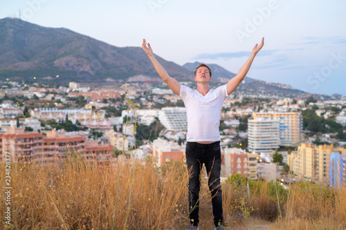 Young Tourist Man With Eyes Closed And Open Arms While Standing On Top Of The Hill