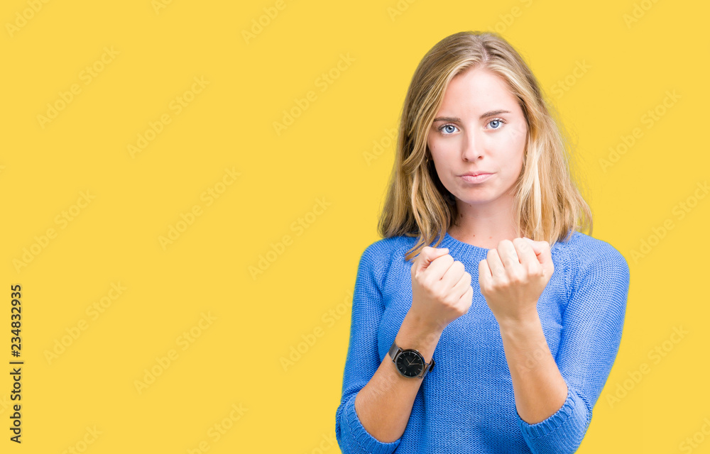 Beautiful young woman wearing blue sweater over isolated background Ready  to fight with fist defense gesture, angry and upset face, afraid of problem  Stock Photo | Adobe Stock